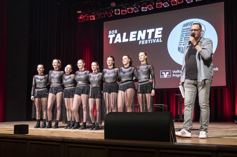 Tanzgruppe auf der Bühne beim SOS-Talentefestival mit Moderator.
