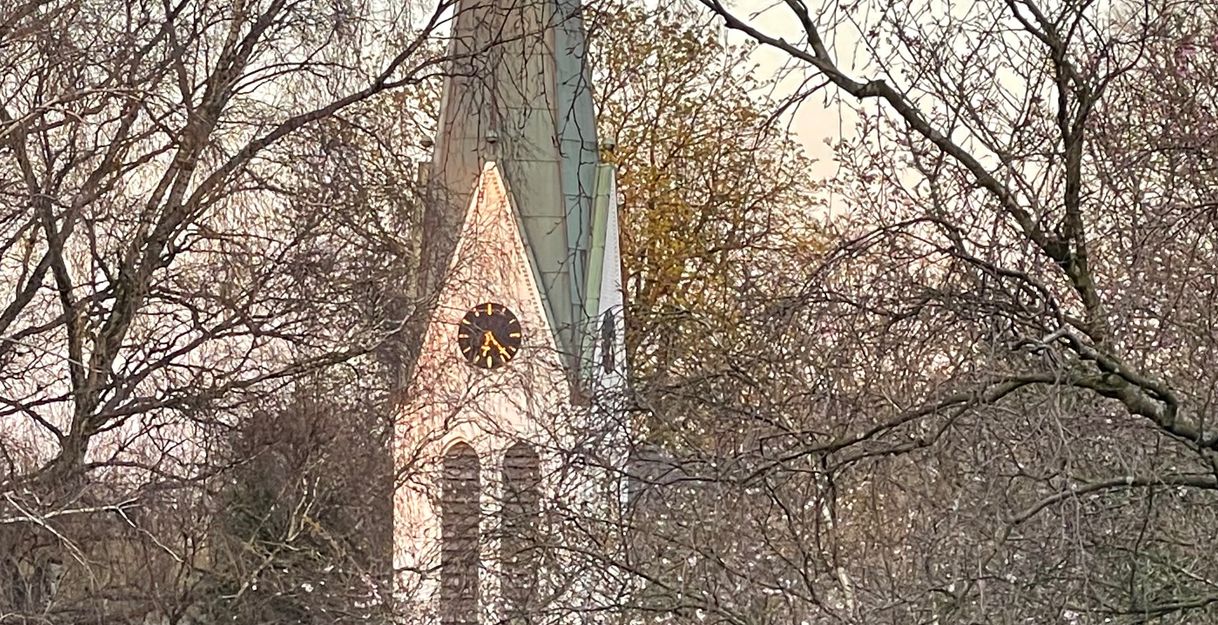 Kirchturm der St. Anschar Kirche hinter kahlen Bäumen.