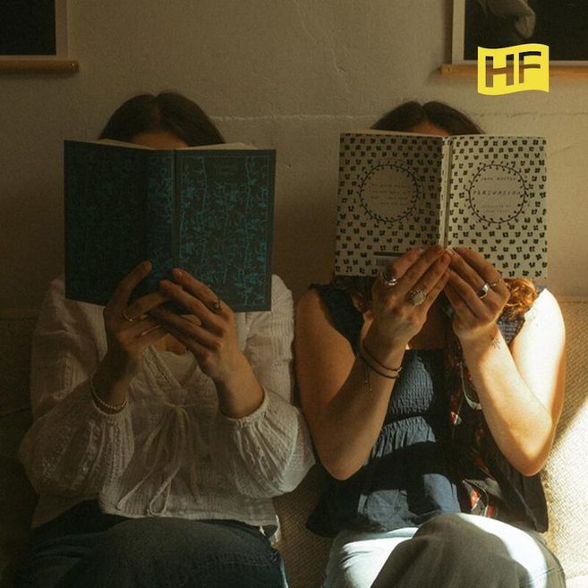 Zwei Personen sitzen auf einem Sofa und lesen Bücher, die ihre Gesichter verdecken. Ein gelbes Logo mit den Buchstaben 'HF' ist oben rechts zu sehen.