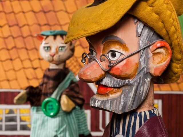 Puppen von Pettersson und Findus vor einem Haus mit Ziegeldach.