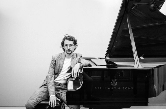 Ein Mann sitzt lässig an einem Steinway & Sons Flügel.