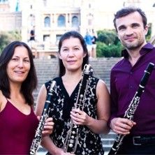 Drei Personen mit Klarinetten vor einem Gebäude.