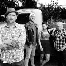 Schwarz-weiß Foto einer vierköpfigen Band vor einem alten Auto.