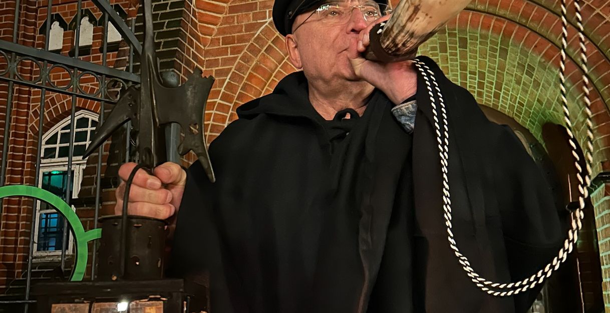 Der Nachtwächter bläst vor dem Schloss zum historischen Rundgang durch Bergedorfs Altstadt in sein Horn