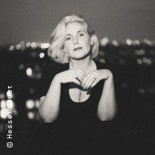 Schwarz-weiß Foto einer Frau mit blonden Haaren vor unscharfem Hintergrund.