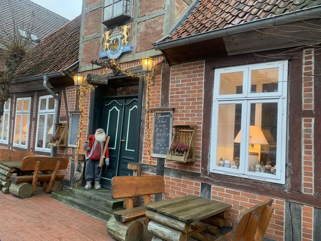Weihnachtszauber im Bleckeder Brauhaus: festlich geschmückter Eingang mit Lichterketten, Weihnachtsmannfigur und rustikalen Holzbänken vor dem Backsteingebäude.
