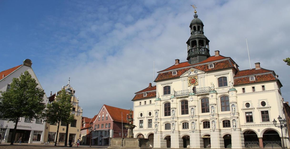 Historisches Rathaus mit Turm und umliegenden Gebäuden auf einem Platz bei klarem Himmel.