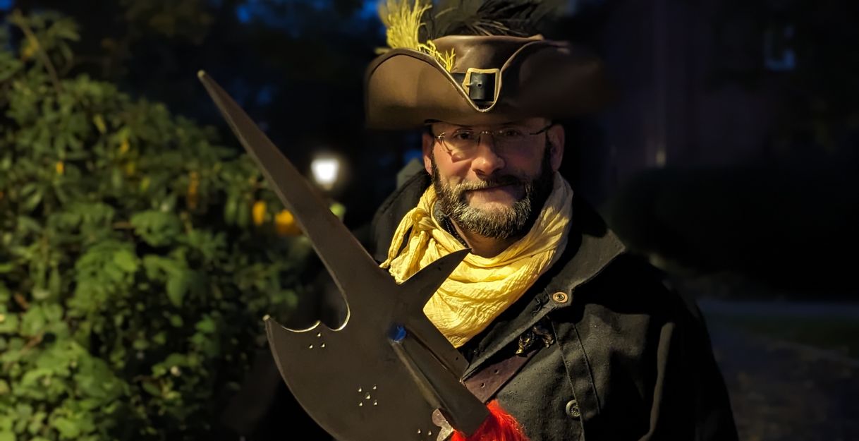 Mann in historischer Kleidung mit Hellebarde bei Nacht