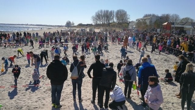 Viele Menschen, darunter viele Kinder, nehmen an einer Ostereiersuche am Strand teil.