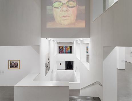 Innenansicht eines modernen Museums mit weißen Wänden und Kunstwerken an den Wänden.