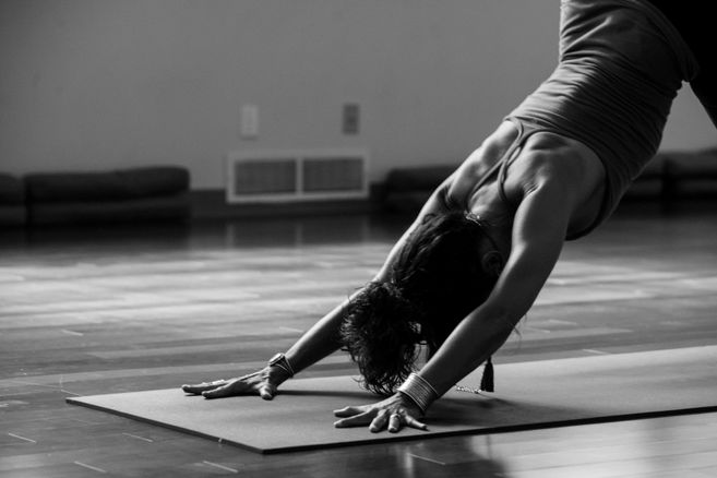 Eine Person in einer Yoga-Pose auf einer Matte in einem Raum.