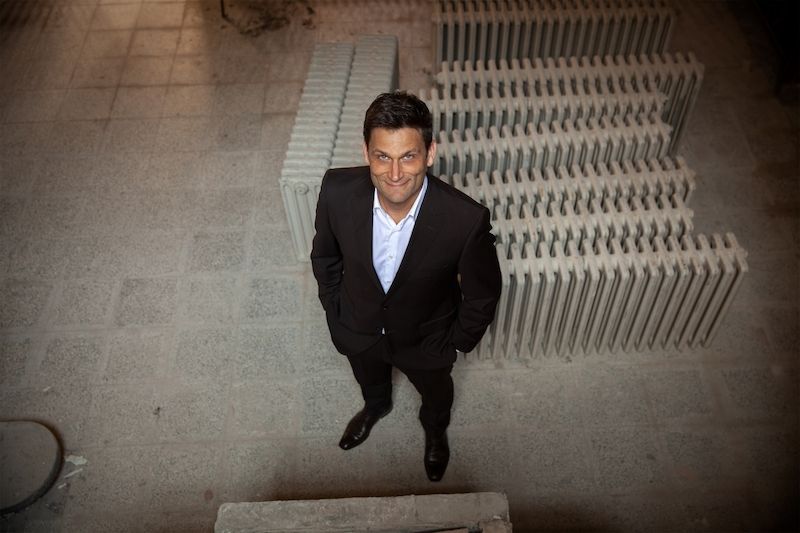 Mann im Anzug steht auf einem Boden mit Heizkörpern.