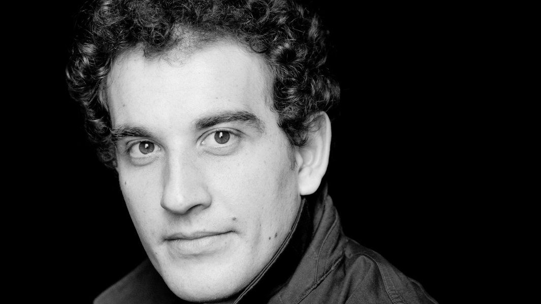 Porträt eines Mannes mit lockigem Haar in Schwarz-Weiß.