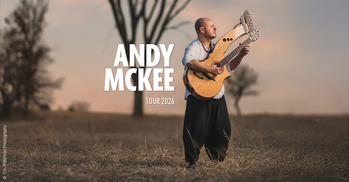 Ein Mann steht auf einem Feld und spielt eine Harfengitarre, während die Abenddämmerung den Himmel färbt. Der Text 'Andy McKee Tour 2026' ist eingeblendet.