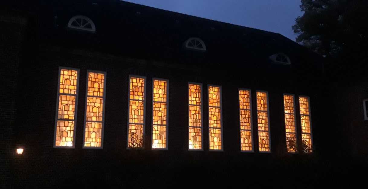 Außenansicht eines Gebäudes mit erleuchteten Fenstern bei Nacht.