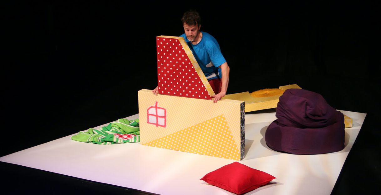 Eine Person arrangiert bunte, gepolsterte Blöcke auf einer Bühne.