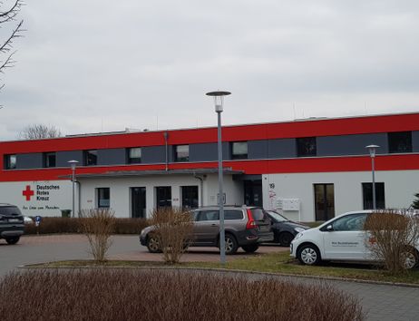 Gebäude des Deutschen Roten Kreuzes mit geparkten Autos davor.