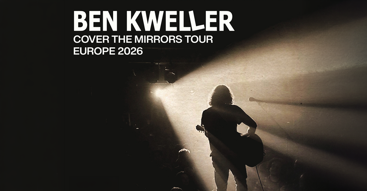 Schattenriss eines Gitarristen auf der Bühne mit Lichtstrahlen im Hintergrund.