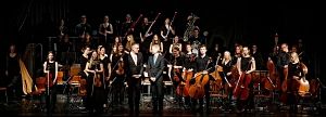 Ein Orchester auf einer Bühne mit Musikern und Dirigenten.