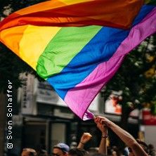 Regenbogenflagge wird von Menschen in einer Menschenmenge gehalten.