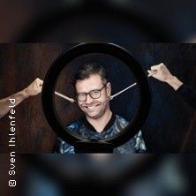 Ein Mann mit Brille lächelt durch einen runden Rahmen, während zwei Hände ein Gummiband um seinen Kopf spannen.