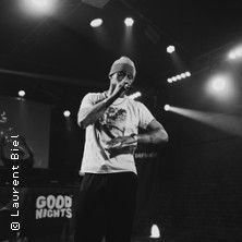 Ein Musiker performt auf einer Bühne mit Mikrofon in der Hand.