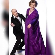 Ein Paar in auffälliger Kleidung posiert humorvoll vor einem weißen Hintergrund.