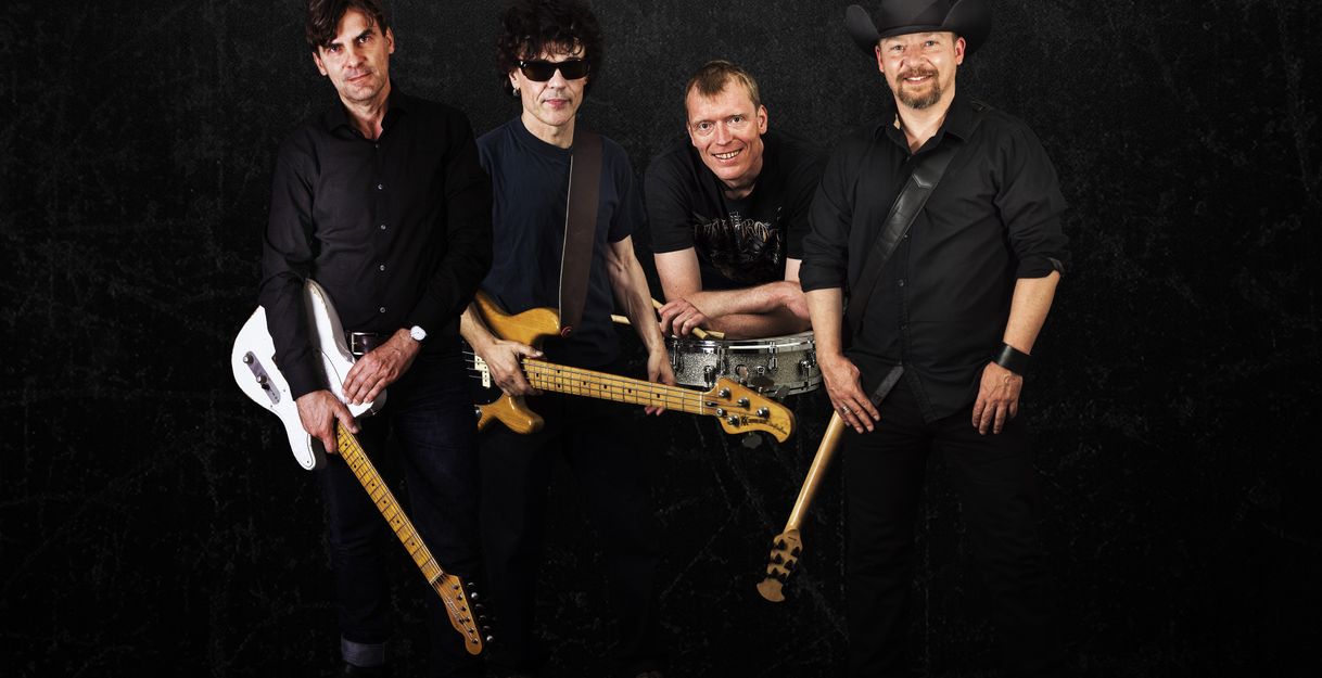 Vier Männer mit Musikinstrumenten vor schwarzem Hintergrund.