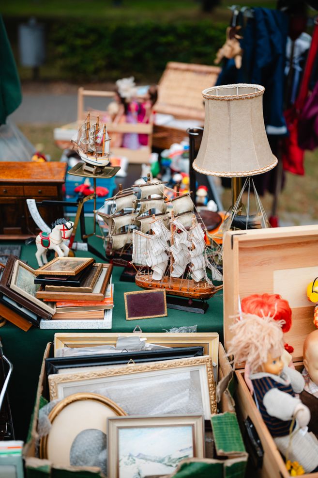 Flohmarktstand mit Modellschiffen, Bilderrahmen und einer Lampe.