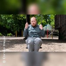 Ein Mann sitzt auf einer Schaukel in einem Park.