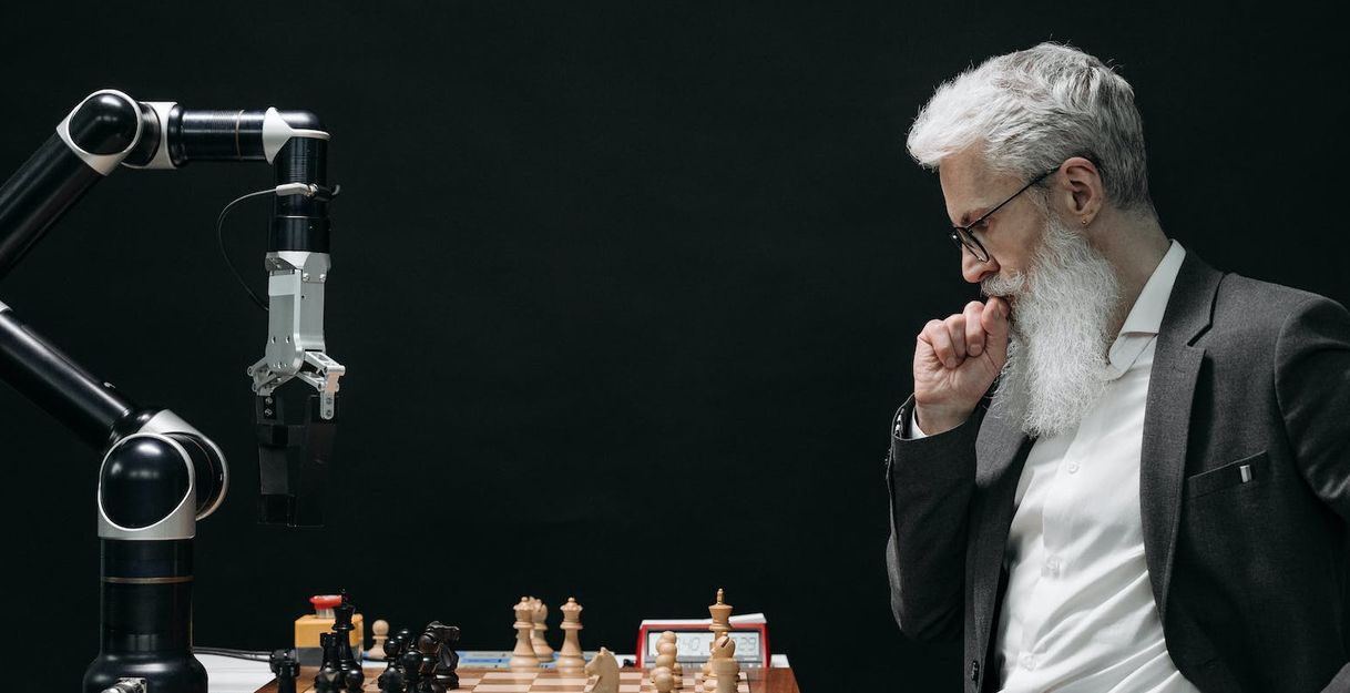 Ein Mann mit weißem Bart spielt Schach gegen einen Computer.