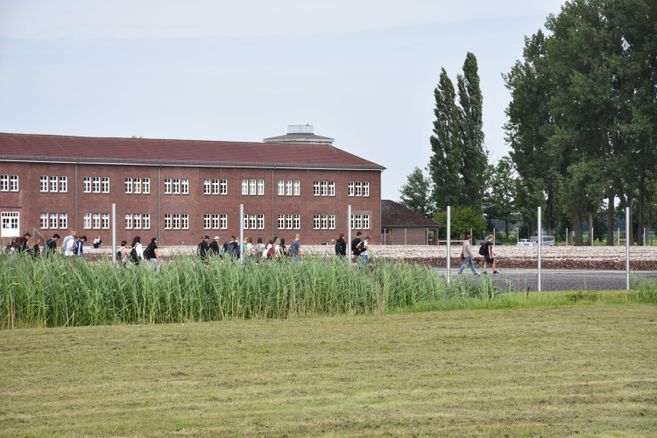Das Gelände der Gedenkstätte, ein Klinkerhaus, im Vordergrund eine Wiese und eine Gruppe Menschen