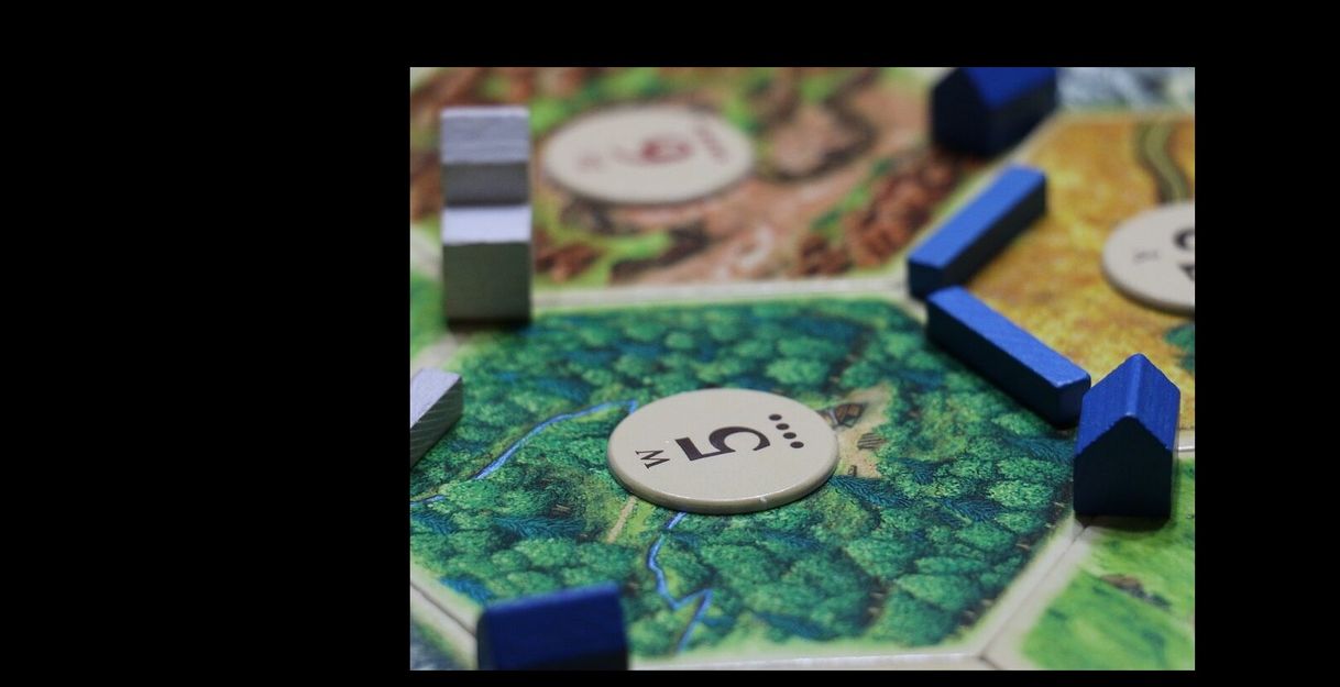 Nahaufnahme eines Brettspiels mit blauen und grauen Spielsteinen auf einem Wald-Feld.