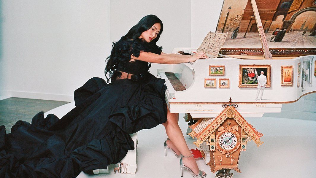 Frau in schwarzem Kleid spielt verzierten weißen Flügel.