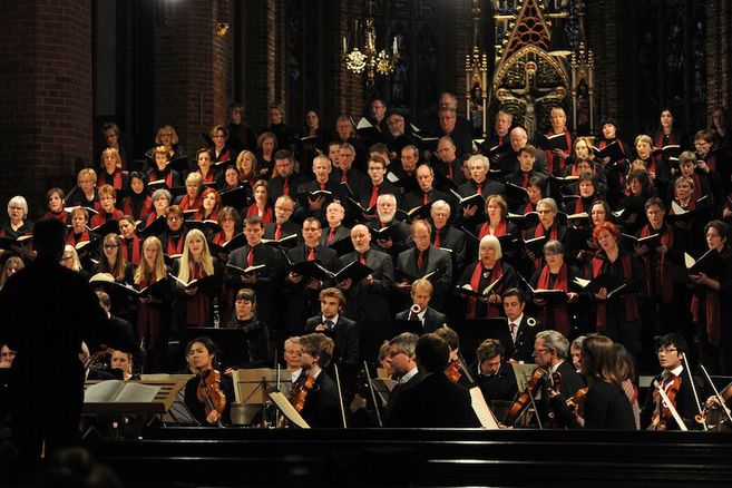 Ein Chor und Orchester führen ein klassisches Musikstück in einer Kirche auf.