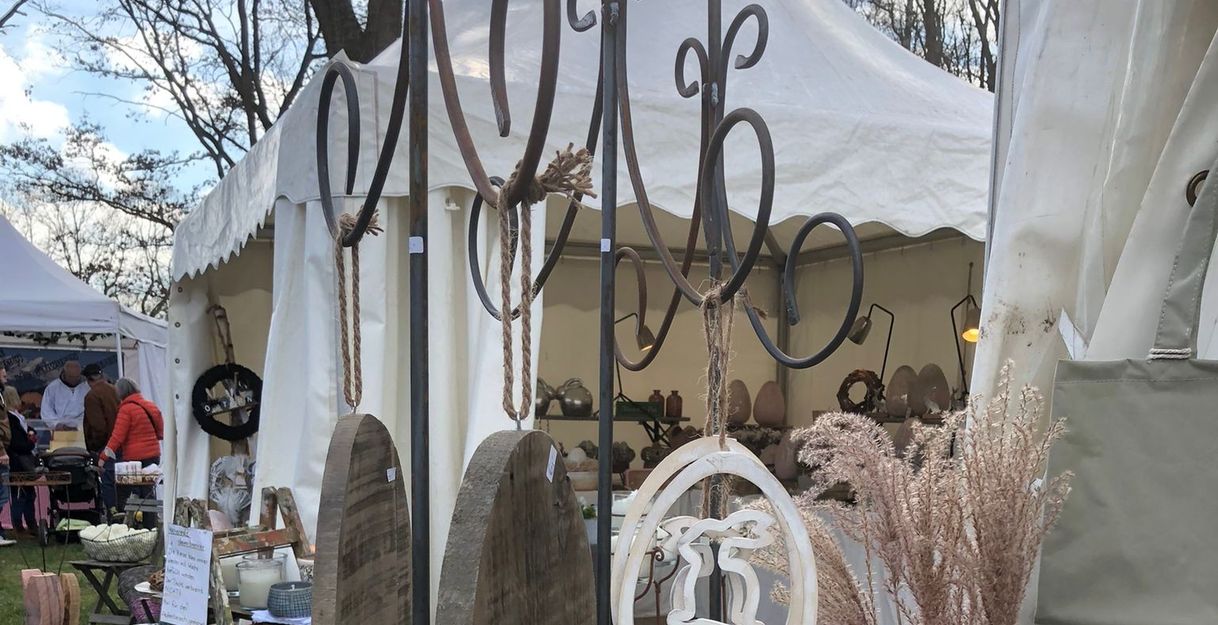 Ein Marktstand mit dekorativen Holzartikeln und einem weißen Zelt im Hintergrund.