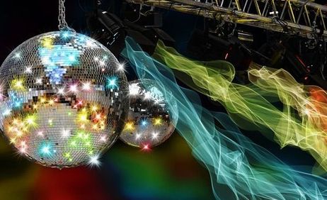 Zwei Discokugeln hängen von der Decke, umgeben von bunten Lichteffekten und Nebel.