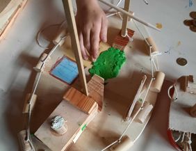Kind baut Modellschiff aus Holz und Korken.