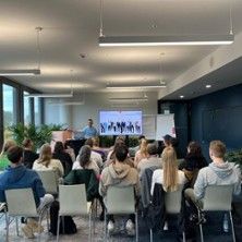 Ein Vortrag in einem modernen Konferenzraum mit vielen Zuhörern, die einem Präsentator zuhören.