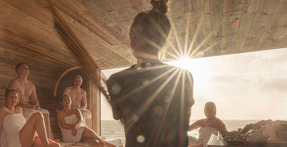 Menschen in einer Sauna mit Sonnenlicht, das durch ein Fenster scheint.