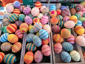 Bunte, gestreifte Ostereier in Holzkisten auf einem Markt.