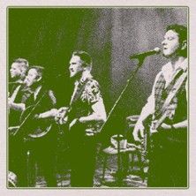 Vier Musiker auf einer Bühne mit Mikrofonen und Instrumenten.