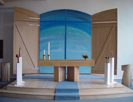 Moderner Kirchenaltar mit blauem Hintergrund und Holzverkleidung.