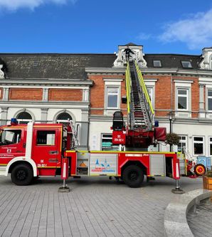 Feuerwehrfahrzeug mit ausgefahrener Leiter vor einem historischen Gebäude.