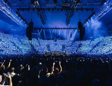 Großes Konzert mit Chor und Publikum in einer beleuchteten Arena.