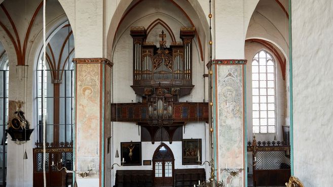 Innenansicht einer Kirche mit einer großen Orgel und gotischen Bögen.