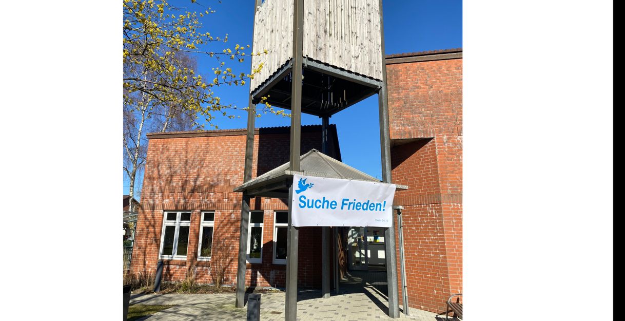 Eingang eines Backsteingebäudes mit einem Banner, das "Suche Frieden!" zeigt.