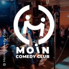 Logo des Moin Comedy Clubs vor einem Publikum bei einer Open-Mic-Veranstaltung.