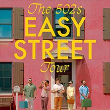 Fünf Personen stehen vor einem rosa Gebäude mit gelben Fensterläden, der Text 'The 502s Easy Street Tour' ist darüber geschrieben.