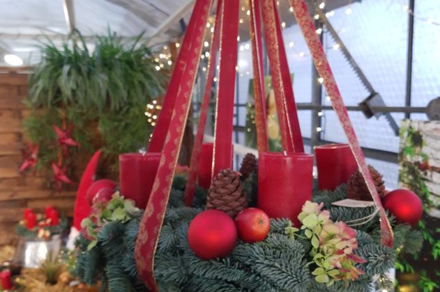 ein Adventskranz mit roten Bändern und Kerzen